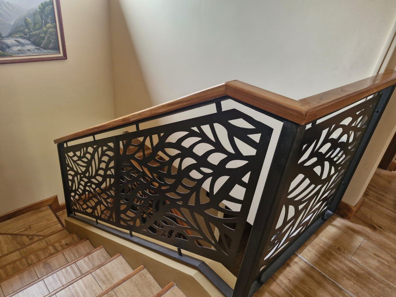 Baranda de escalera con motivo de hojas y pasamanos de madera